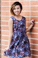 sorridente snello asiatico americano donna in piedi nel vestito foto