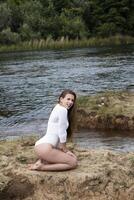 caucasico adolescente ragazza seduta su fango isola nel fiume foto