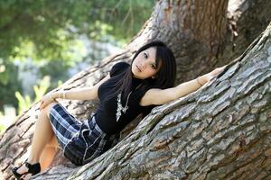 giovane asiatico americano donna gonna reclinabile nel albero foto