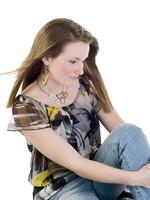 giovane donna seduta su pavimento nel jeans e camicetta foto