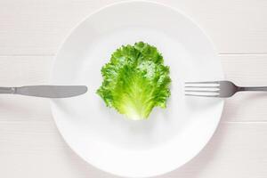 foglia lattuga su bianca piatto con forchetta e coltello, disintossicazione mono dieta per peso perdita foto