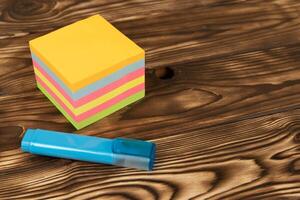un' pila di colorato Appunti, promemoria adesivi e un' blu marcatore su un' di legno tavolo. organizzazione, pianificazione foto