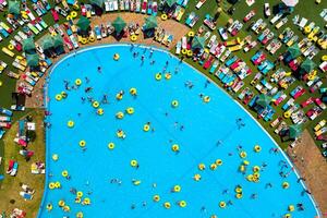 superiore Visualizza di persone rilassante nel il piscina su giallo gonfiabile cerchi e sole letti su il spiaggia foto