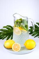 un' brocca di limonata con Limone fette, fresco menta e ghiaccio cubi su il tavolo. fabbricazione fresco limonata. avvicinamento. foto