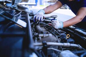 avvicinamento tiro di auto meccanica mani Lavorando su auto motore nel riparazione negozio. auto servizio tecnico opera nel riparazione negozi e Manutenzione Servizi foto