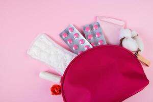 borsa cosmetica rosa e prodotti per l'igiene femminile per le mestruazioni. assorbenti, tamponi, compresse. foto