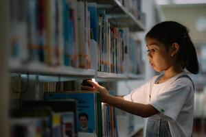 un' giovane ragazza è guardare a un' libro nel un' biblioteca foto