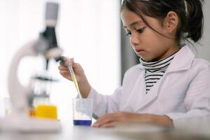 asiatico bambino ragazza apprendimento scienza chimica con test tubo fabbricazione sperimentare a scuola laboratorio. formazione scolastica, scienza, chimica, e figli di concetti. presto sviluppo di bambini. foto