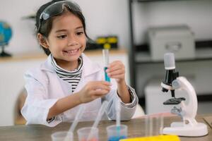 poco carino ragazza con un' microscopio Tenere un' laboratorio bottiglia con acqua sperimentare studia scienziati a scuola. formazione scolastica scienza concetto. foto