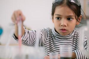 asiatico bambino ragazza apprendimento scienza chimica con test tubo fabbricazione sperimentare a scuola laboratorio. formazione scolastica, scienza, chimica, e figli di concetti. presto sviluppo di bambini. foto