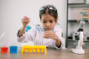 asiatico bambino ragazza apprendimento scienza chimica con test tubo fabbricazione sperimentare a scuola laboratorio. formazione scolastica, scienza, chimica, e figli di concetti. presto sviluppo di bambini. foto