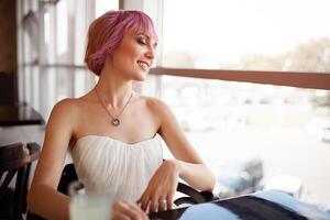 sorridente donna è seduta nel confortevole bar-caffetteria durante sua ricreazione volta, allegro contento femmina riposa dopo opera aspetta sua amici nel accogliente caffè negozio foto