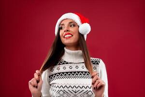 vicino su ritratto bellissimo caucasico donna nel rosso Santa cappello su rosso studio sfondo. Natale e nuovo anno vacanza concetto. foto