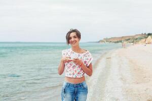 bellissimo donna rilassare durante esotico vacanza su il spiaggia godendo dolce caffè foto