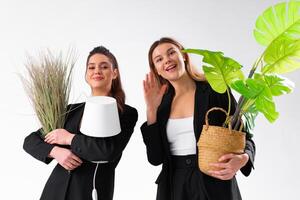 Due giovane attività commerciale donna vestito nero completo da uomo Sorridi Tenere pianta della casa e lampada in piedi isolato su bianca sfondo. in movimento concetto. delocalizzazione nuovo ufficio con positivo. foto