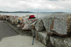 Due pesca canne attaccare su di pietre, su il spiaggia nel morgat Francia 29 Maggio 2018 foto