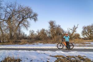 anziano ciclista con un' montagna bicicletta è assunzione un' riposo fermare su poudre fiume pista vicino Greeley, Colorado, nel inverno scenario foto