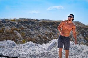 in forma allenato uomo a piedi su con blu cielo. bello muscolare forte uomo con nudo torso all'aperto. foto