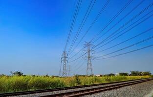 Due torri di alta tensione elettricità poli quello attraversare al di sopra di il doppio binario Ferrovia brani foto