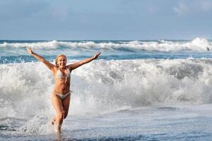 un' ragazza con bagnato capelli salti al di sopra di grande onde nel il atlantico oceano, in giro un' onda con spruzzi di spray e acqua gocce.tenerife.spagna foto