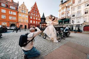 un' fotografo fotografie un' sposa nel un' nozze vestito con lungo capelli nel il vecchio cittadina di Breslavia. nozze foto sparare nel il centro di un vecchio polacco città.breslavia, Polonia