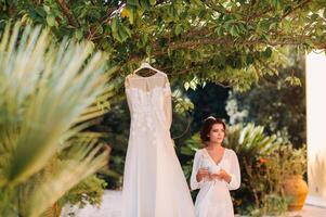 un' bellissimo sposa sta Il prossimo per un' nozze vestito con un' tazza di tè nel un' boudoir attrezzatura Il prossimo per un' villa nel italia.mattina di il sposa nel Toscana foto