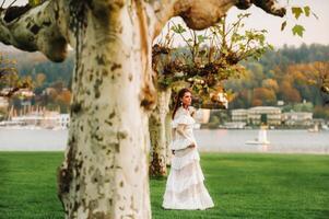 un' sposa nel un' bianca nozze vestito con un' cintura nel il vecchio cittadina di velden am meglio vedere un modello nel un austriaco nozze vestito.alpi foto