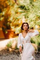 un' bellissimo sposa è seduta su un' sedia e sorridente nel sua biancheria intima e condimento toga Il prossimo per un' villa nel italia.mattina di il sposa nel Toscana foto