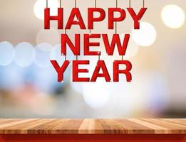felice anno nuovo parola di legno rosso appesa sul tavolo di legno foto