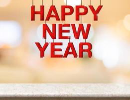 felice anno nuovo parola in legno rosso appesa sul tavolo di marmo foto