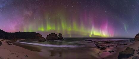 ai generato aurora australiano. spettacolare Schermo di vivace verde e rosa luci pittura il notte cielo sopra un australiano spiaggia. stelle scintillio come onde delicatamente carezza il roccioso litorale. foto