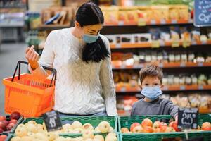 madre e figlio siamo shopping a il drogheria negozio. essi indossare maschere durante quarantena. coronavirus pandemia .coved-19 veloce. il epidemico di il virus. foto