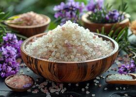 ai generato di legno ciotola pieno con rosa himalayano sale e cucchiaio circondato di viola fiori e di legno ciotola di sale. foto