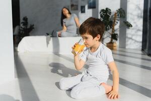 mamma con figlio nel pigiama mangiare frutta su letto. ritratto felice, sorridente, gioioso famiglia, madre e figlio avendo prima colazione nel letto, sorpresa su mamma giorno. positivo umano emozioni foto