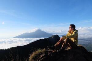 sopra nube nove, montare batur's picco, asiatico uomo trekker sotto azzurro cielo e nube mare foto