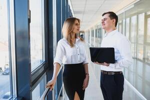 opera nel ufficio. genere uomo Tenere il computer portatile mentre guardare a il suo compagno foto