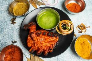 speziato tandoori pollo lal badsha con chili salsa servito nel un' piatto isolato su grigio sfondo superiore Visualizza di bangladesh cibo foto
