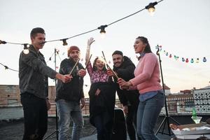 vista frontale. cibo e bottiglia sul tavolo. giocando con le stelle filanti sul tetto. gruppo di giovani belle amiche foto