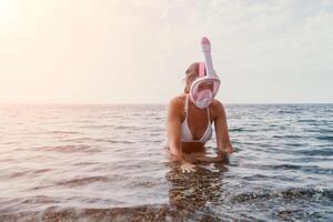 giovane contento donna nel bianca bikini e indossare rosa maschera prende pronto per mare snorkeling. positivo sorridente donna rilassante e godendo acqua attività con famiglia estate viaggio vacanze vacanza su mare. foto