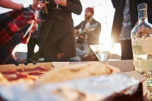 pizza e alcol sullo sfondo di persone con drink e uomo con chitarra foto