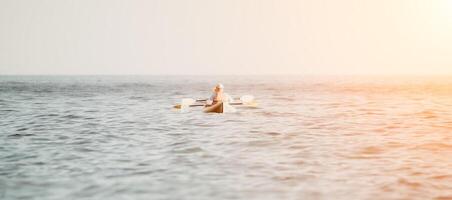 contento coppia kayak nel un gonfiabile kayak su il mare a tramonto. coppia canoa nel il mare vicino il isola con montagne. persone kayak nel vita giacche vela. indietro Visualizza foto