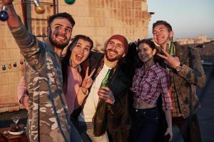 gesti per l'immagine. il tempo dei selfie per un gruppo di amici positivi si trova sul tetto con il muro dietro foto