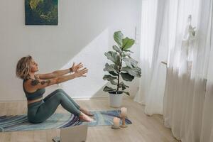 un' 50 anni donna fare in linea yoga a casa foto