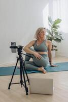 un' 50 anni donna fare in linea yoga a casa foto