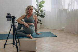 un' 50 anni donna fare in linea yoga a casa foto