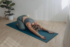 un' 50 anni donna fa yoga a casa foto