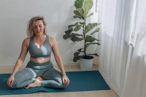 un' 50 anni donna fa yoga a casa foto