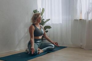 un' 50 anni donna fa yoga a casa foto