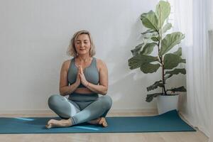 un' 50 anni donna fa yoga a casa foto