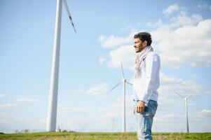 indiano ingegnere in piedi contro mulini a vento foto